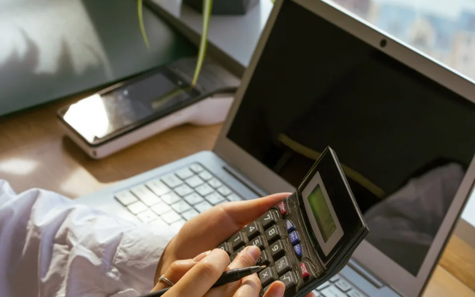 accountant using a calculator at his desk in front of a computer