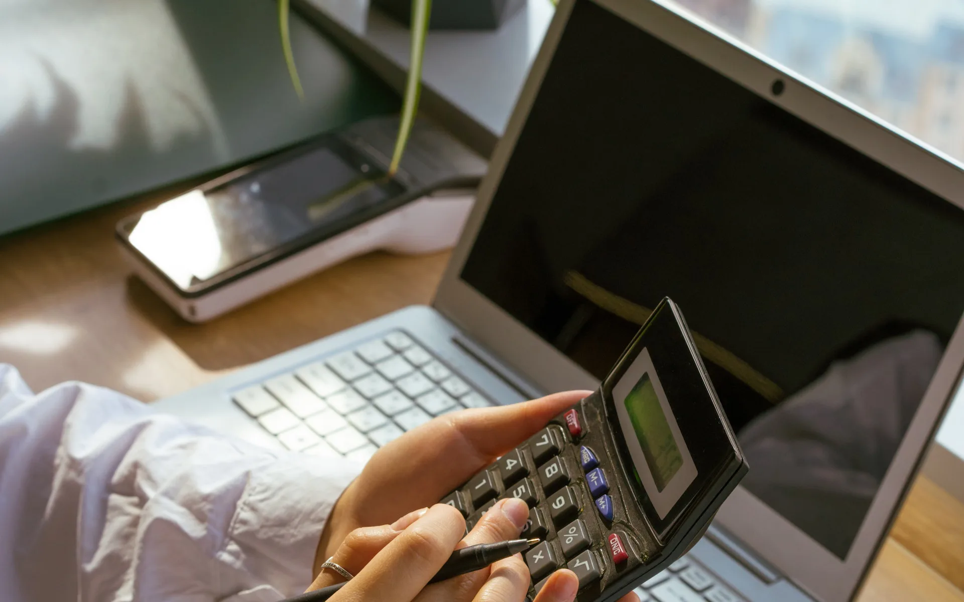 accountant using a calculator at his desk in front of a computer