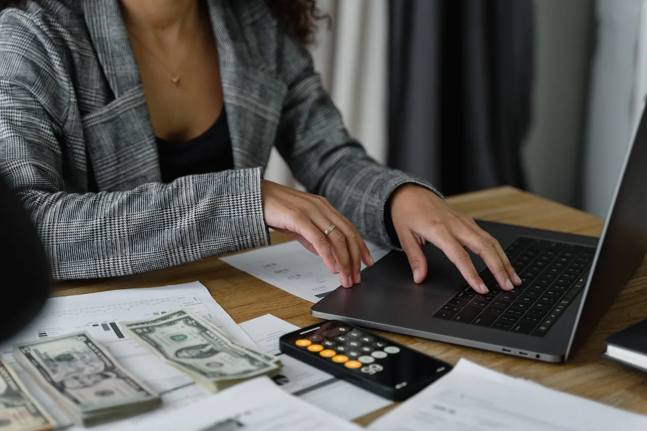 female accounting team member working at her laptop with money on the table