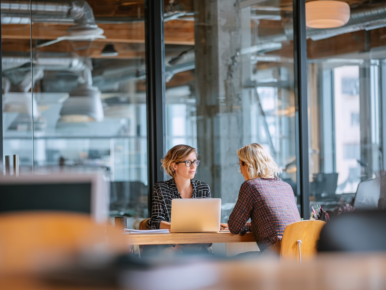 Two colleagues sitting at a conference table with a laptop, representing workflow planning in an accounting firm.